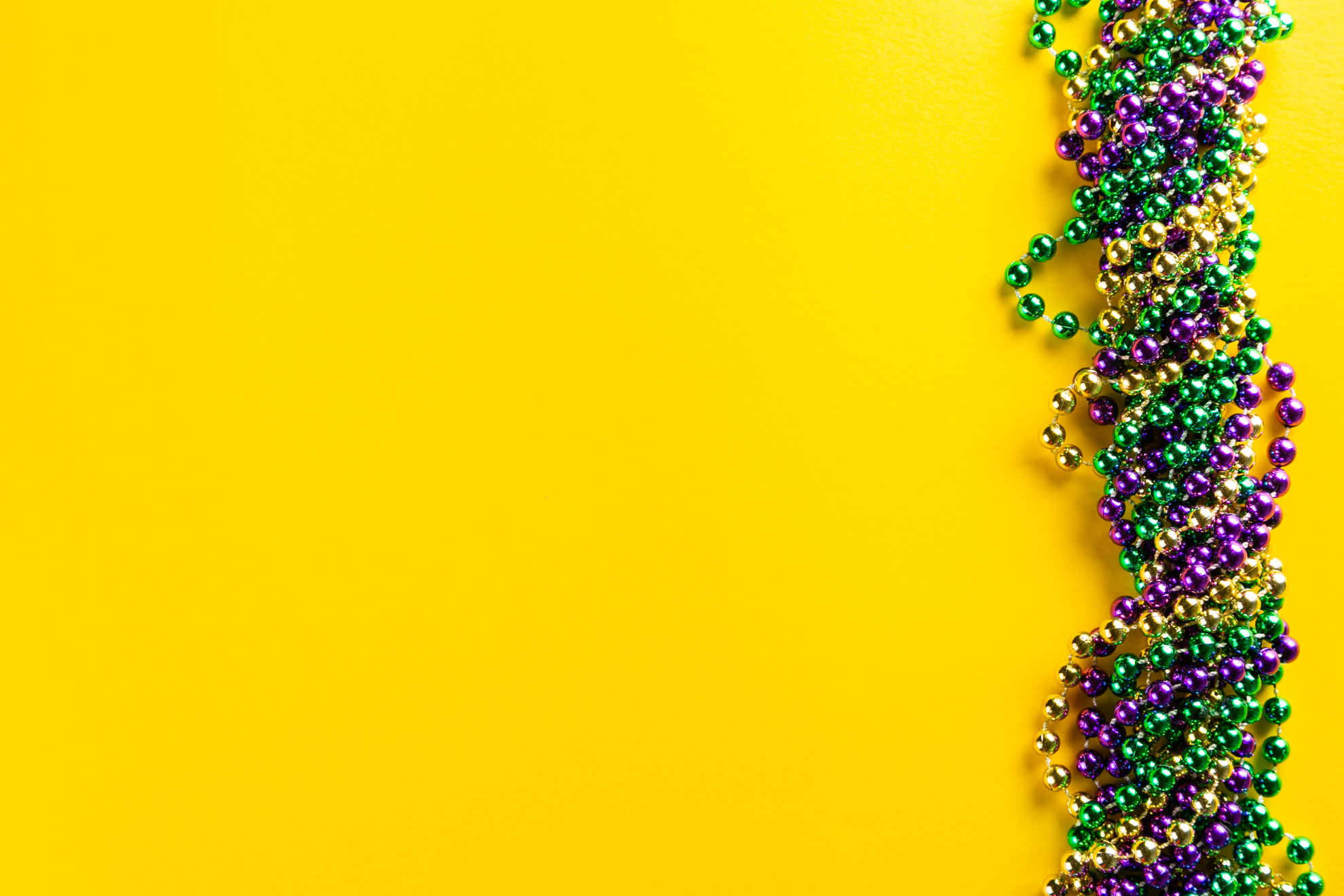 Mardi gras carnival concept - beads on yellow background